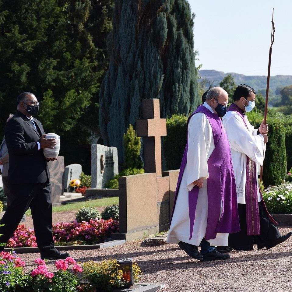 Jiyon Edechelathu (39) trägt die Urne mit der Asche seines Bruders zur letzten Ruhestätte auf dem Bleibuirer Friedhof, vornweg ziehen mit dem Kreuz die Priester Jaison Thazhathil und Thomson Pazhayachirapeedikayil Jose sowie Diakon Manfred Lang.