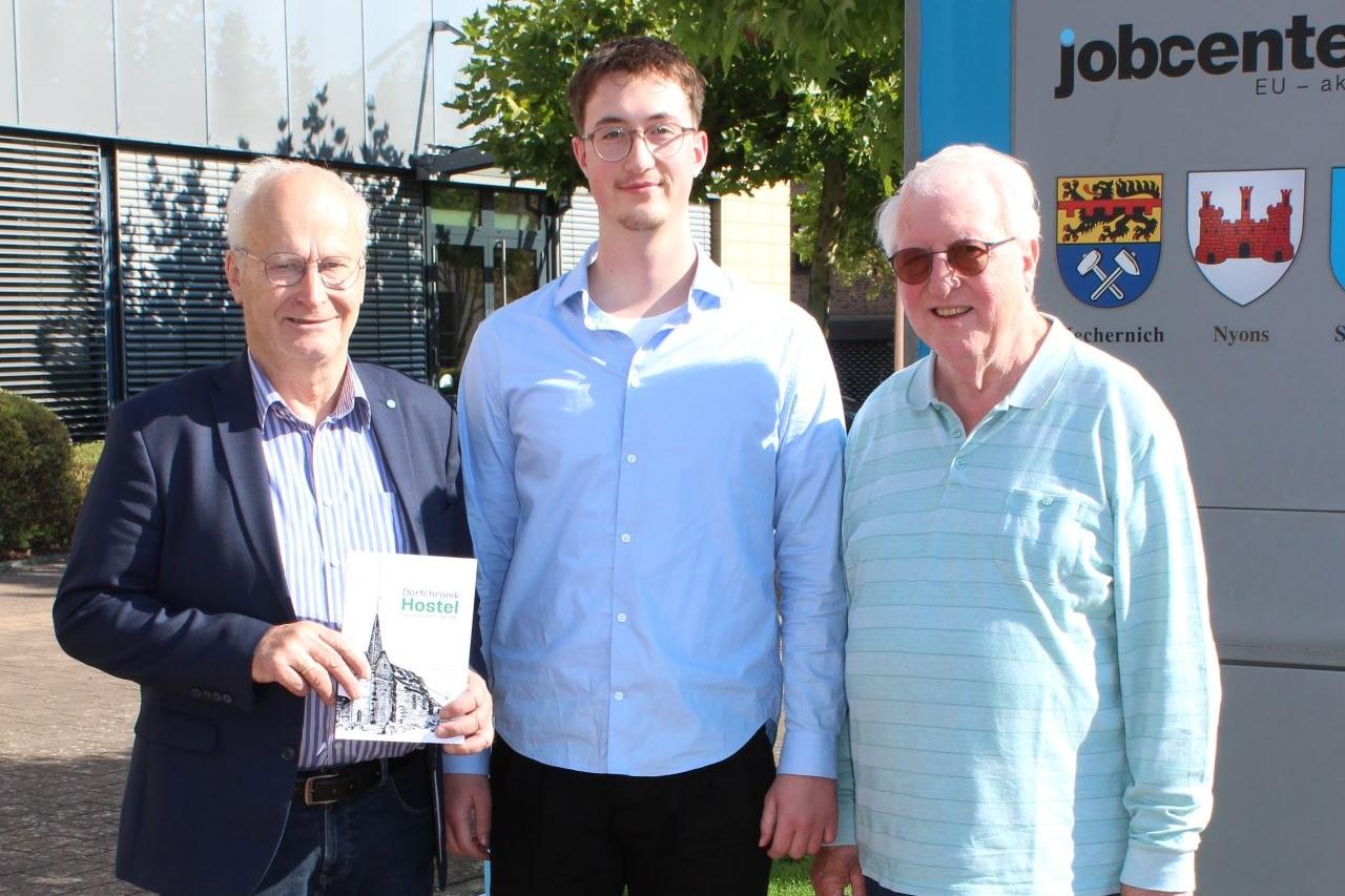 Das erste Exemplar für den ersten Bürger: Noch druckfrisch überreichte Autor Lucas Hamacher (Mitte) die nagelneue Dorfchronik zusammen mit Großvater Dieter Schröder (rechts) an Bürgermeister Hans-Peter Schick, der den 23-Jährigen zu den Recherchen über sein Heimatdorf Hostel ermutigt hatte.