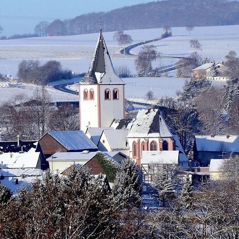 Blick auf das verschneite Glehn mit der Pfarrkirche St. Andreas im Zentrum. Daneben befindet sich der Dorfanger, auf dem zum 2. Advent Weihnachtsmarkt stattfindet.