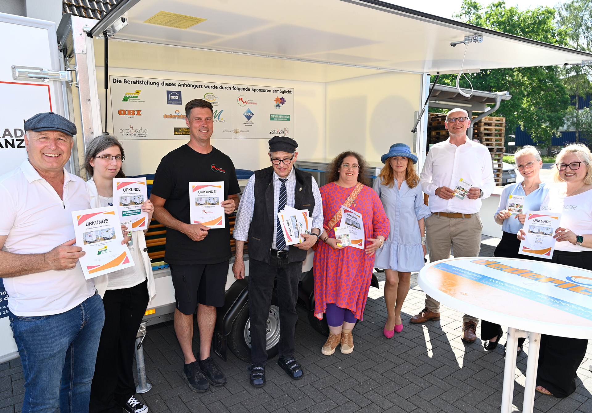 Freuten sich in Esch über den neuen Festanhänger: (v. l.) Wolfgang Schomer (Mechernicher Container Transport), Janina Wirges (Werbeagentur Hedge Mountain Media), Ralf Wucherpfennig (rw elektrik GmbH), Heinz Schmitz (Stellvertretender Bürgermeister von Mechernich), Esther Genz (Großartig Textilgestaltung Bad Münstereifel), Anna Seckler (Pro Mobil), Sebastian Glatzel (Bürgermeister von Bad Münstereifel), Lisa Eckardt (Sachgebietsleitung Tourismus Bad Münstereifel) sowie Stephanie Schmitz (Leiterin des Amtes für Bildung und Tourismus Bad Münstereifel). (c) Foto: Henri Grüger/pp/Agentur ProfiPress