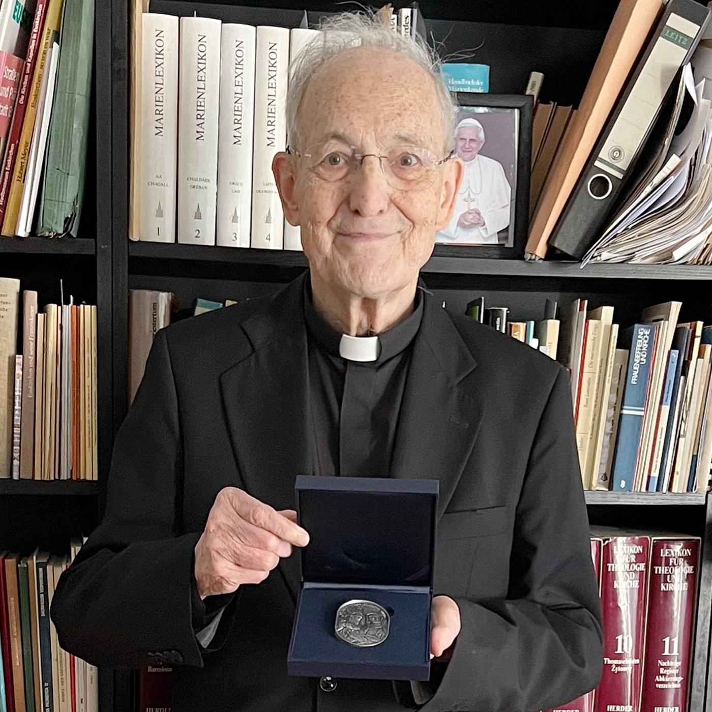 Prälat Prof. Dr. Helmut Müll mit der Geschenkplakette der Deutschen Bischofskonferenz. Die Medaille zeigt die Heiligen Bonifatius und Edith Stein.