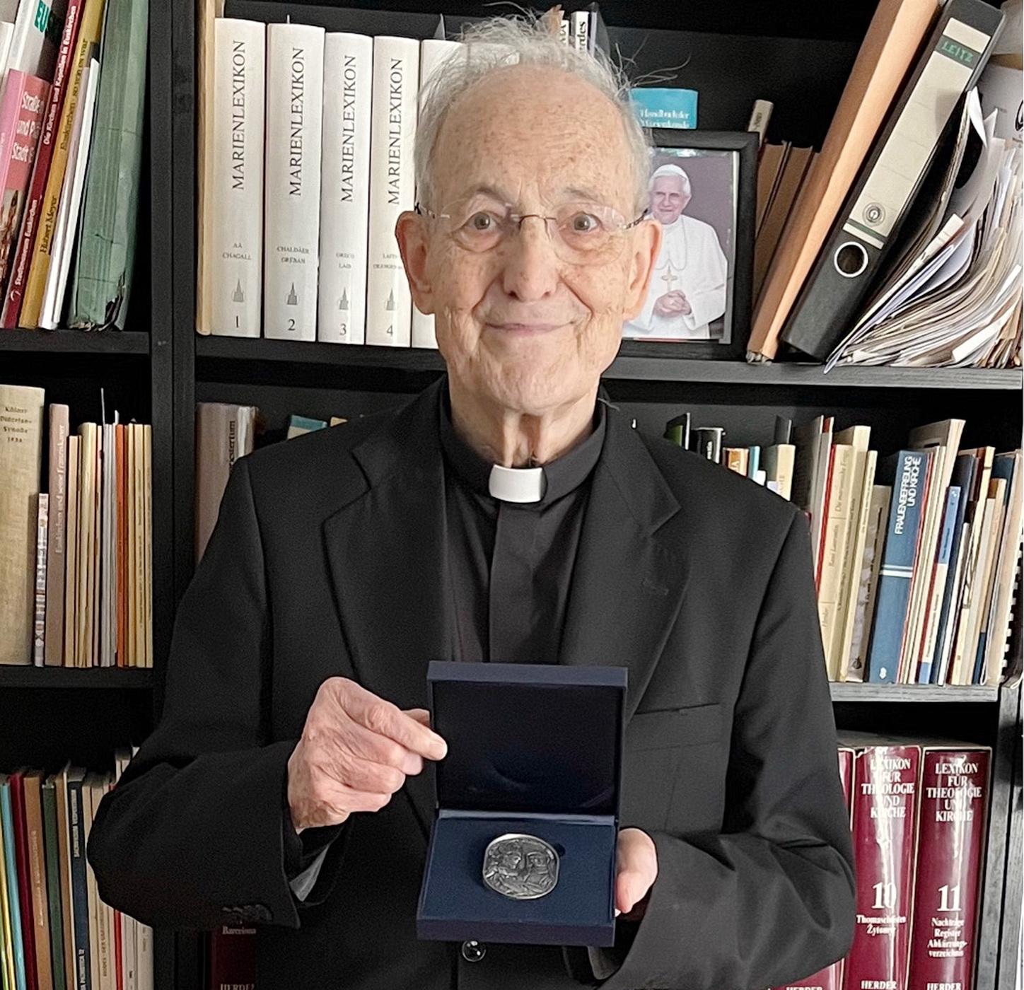 Prälat Prof. Dr. Helmut Müll mit der Geschenkplakette der Deutschen Bischofskonferenz. Die Medaille zeigt die Heiligen Bonifatius und Edith Stein.