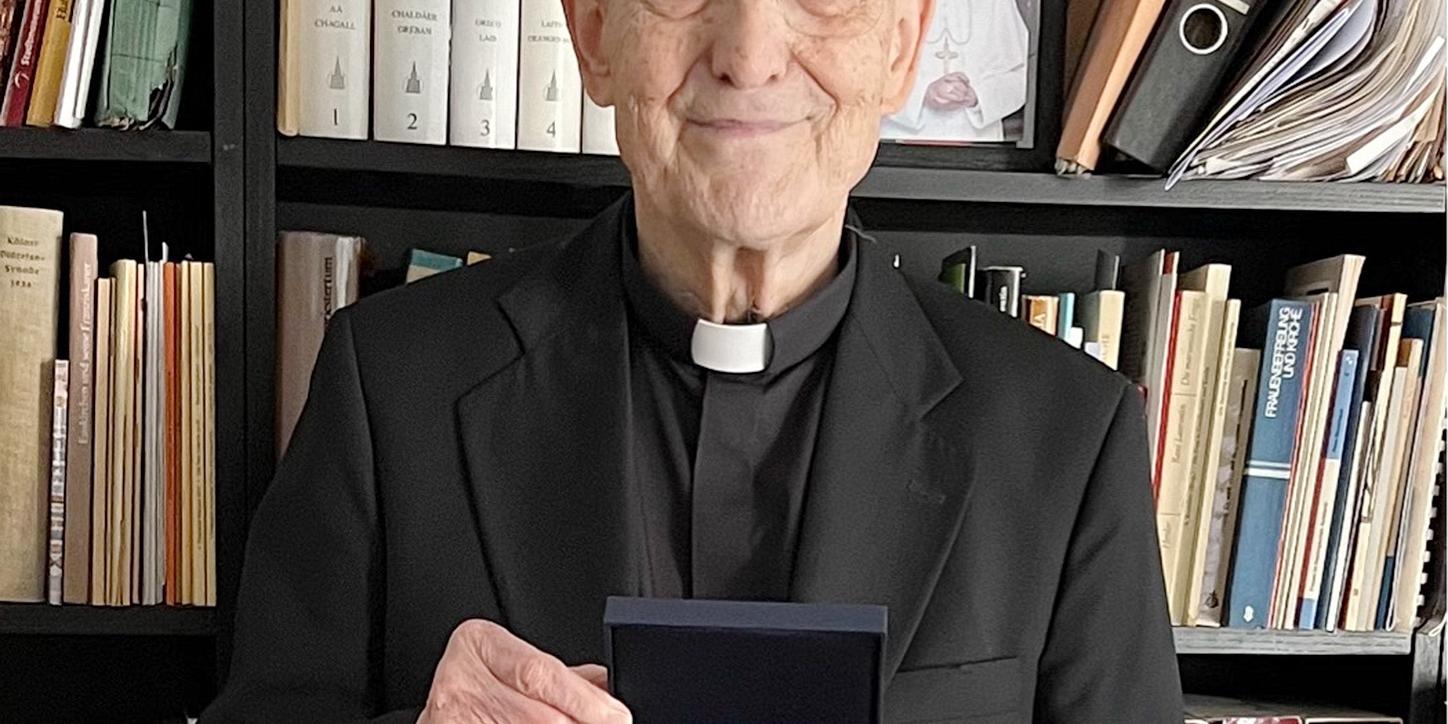 Prälat Prof. Dr. Helmut Müll mit der Geschenkplakette der Deutschen Bischofskonferenz. Die Medaille zeigt die Heiligen Bonifatius und Edith Stein.