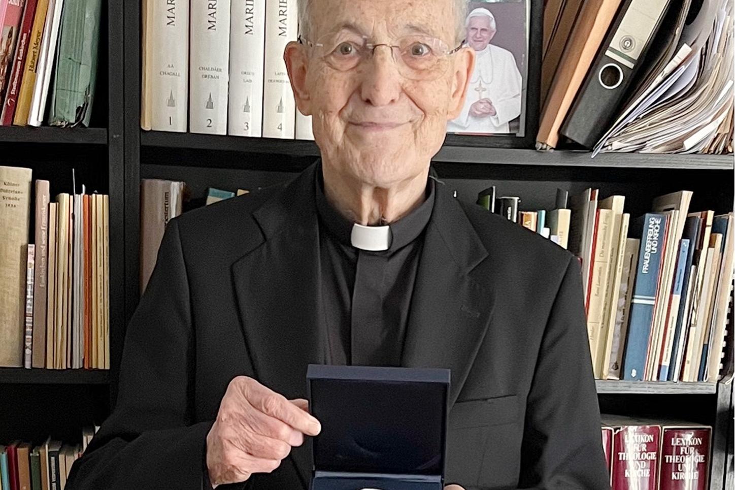 Prälat Prof. Dr. Helmut Müll mit der Geschenkplakette der Deutschen Bischofskonferenz. Die Medaille zeigt die Heiligen Bonifatius und Edith Stein.