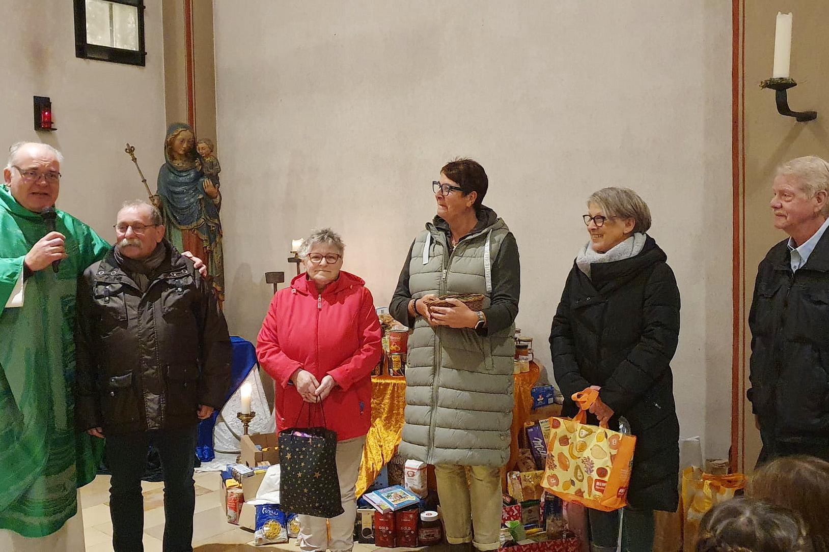 Pfarrer Erik Pühringer und „Tafel“-Chef Wolfgang Weilerswist (v.l.) mit weiteren Vorständen der Mechernicher Wohltätigkeitsorganisation mit gespendeten Lebensmitteln der Gemeindemitglieder am Altar der Pfarrkirche St. Johannes Baptist.