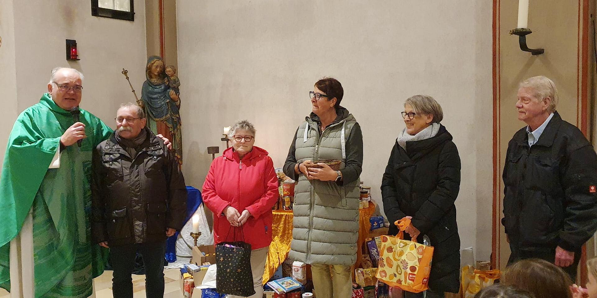 Pfarrer Erik Pühringer und „Tafel“-Chef Wolfgang Weilerswist (v.l.) mit weiteren Vorständen der Mechernicher Wohltätigkeitsorganisation mit gespendeten Lebensmitteln der Gemeindemitglieder am Altar der Pfarrkirche St. Johannes Baptist.