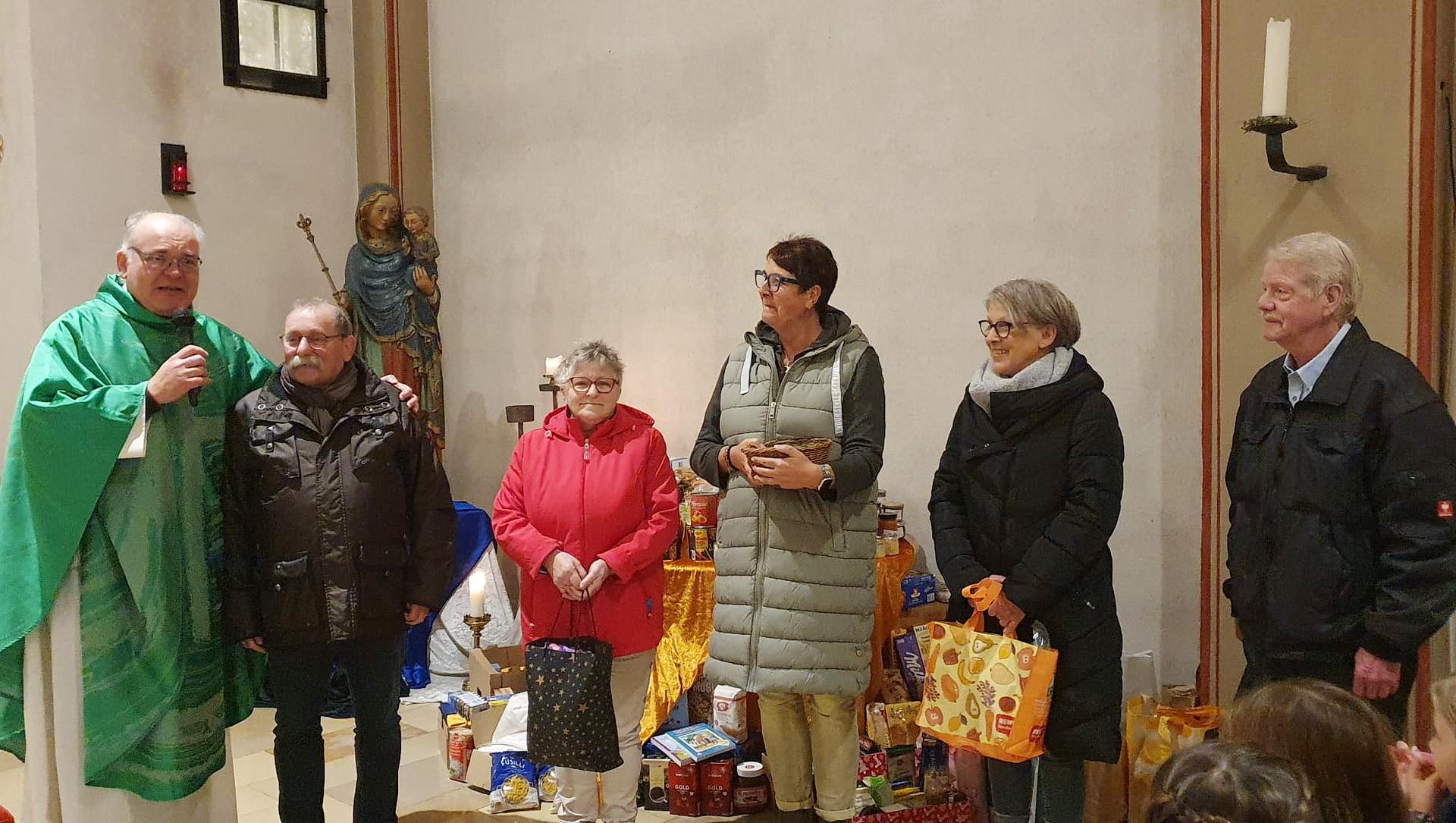 Pfarrer Erik Pühringer und „Tafel“-Chef Wolfgang Weilerswist (v.l.) mit weiteren Vorständen der Mechernicher Wohltätigkeitsorganisation mit gespendeten Lebensmitteln der Gemeindemitglieder am Altar der Pfarrkirche St. Johannes Baptist.
