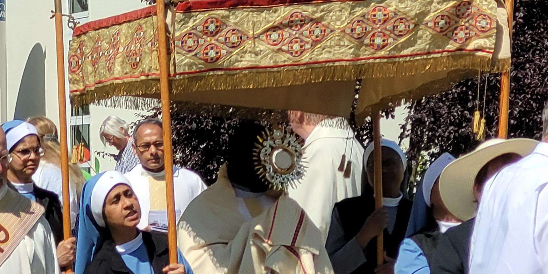 Der ugandische Priester Patrick Mwanguhya trägt das Allerheiligste in der Monstranz, indische Samaritan-Ordensschwestern tragen den „Himmel“, im Hintergrund Pfarrer Erik Pühringer und Generalsuperior Jaison Thazhathil.