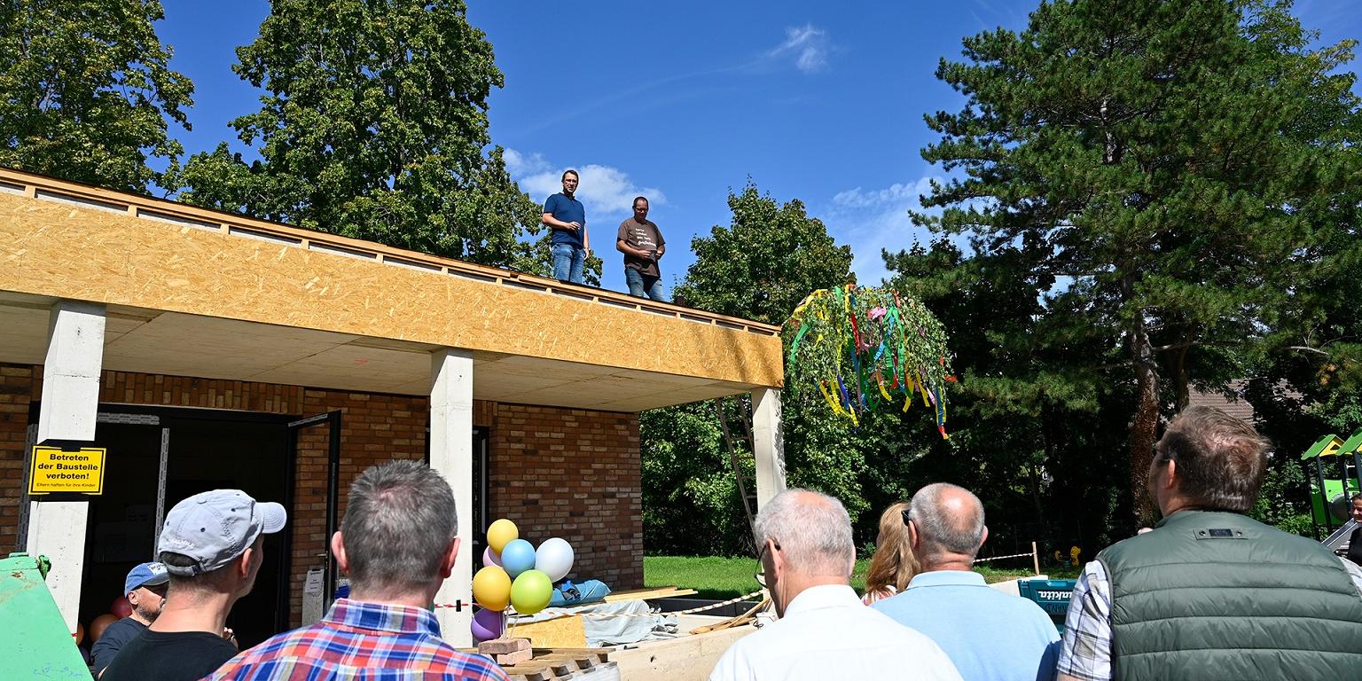 Beim Richtfest des neuen Dorfgemeinschaftshauses in Breitenbenden schauten die Anwesenden neugierig auf zu Ortsbürgermeister Bernd Wienand (o. l.) und Heinz Loosen (o. r.), der die Federführung bei der Eigenleistung innehatte.