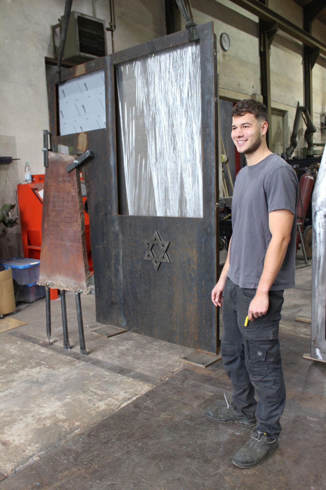 Der 23-jährige Metallbaumeister Jannis Müller aus Hostel schuf das neue Mahnmal aus Cortenstahl, in das die bisherige Stele und auf ansprechende Weise künstlerisch integriert wurde. (c) Foto: Kerstin Rottland/pp/Agentur ProfiPress